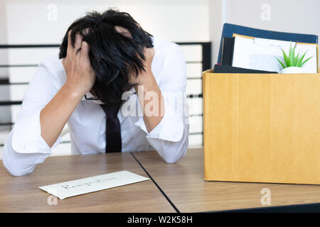 Stressed businessman va être démission et effets personnels d'emballage société et fichiers dans boîte en carton brun, changeant et démissionnera de travail conceptuel Banque D'Images