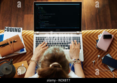 Vue de dessus de la jeune femme assise sur le canapé dans le salon moderne test de logiciels et l'écriture de code. Banque D'Images