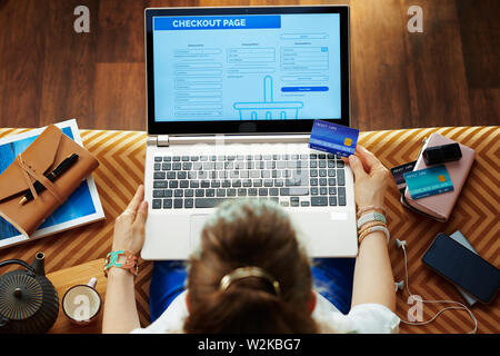 Vue supérieure de l'élégant avec finition de carte de crédit Processus de boutique en ligne tout en restant assis sur le canapé dans le salon moderne. Banque D'Images