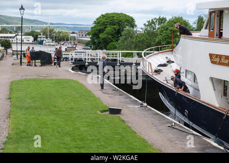 "Lady Rose" en passant par les écluses du Canal Calédonien, Muirtown, Inverness, avec pont Kessock à distance Banque D'Images