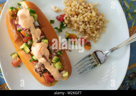 Hot-dog et tiré sur un petit pain de porc garni de salade israélienne et la vinaigrette avec du couscous sur le côté Banque D'Images