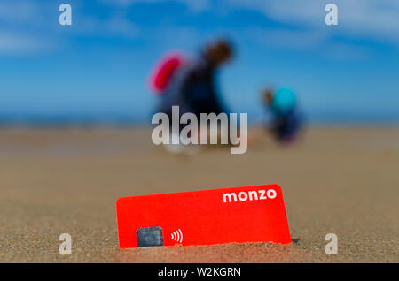 Carte bancaire Monzo dans le sable sur la plage ensoleillée. La photo en gros plan. Banque D'Images