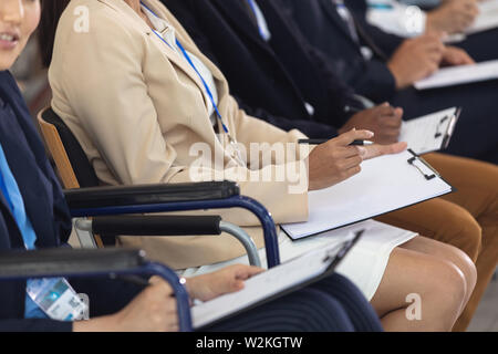 Businesswomen sitting lors de l'écoute de discours dans la salle de conférence Banque D'Images
