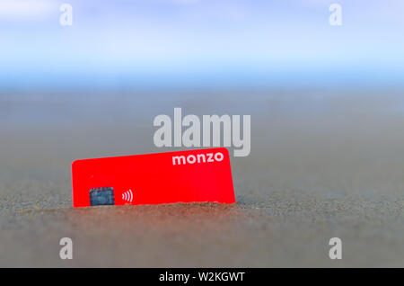 Carte bancaire Monzo dans le sable sur la plage ensoleillée. La photo en gros plan. Banque D'Images