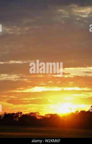 Coucher de soleil sur les champs de Suffolk, été orange jaune soleil avec des nuages sombres Banque D'Images