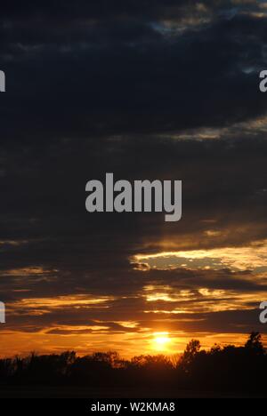 Coucher de soleil sur les champs de Suffolk, été orange jaune soleil avec des nuages sombres Banque D'Images