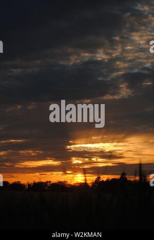 Coucher de soleil sur les champs de Suffolk, été orange jaune soleil avec des nuages sombres Banque D'Images