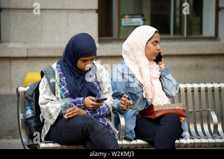 Deux filles musulmanes assis sur un banc Banque D'Images