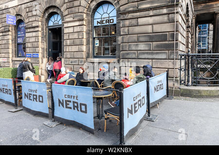 Les clients d'entrer et s'asseoir à l'extérieur d'un Caffè nero en sortie de la Royal Mile, le centre d'Édimbourg, Écosse, Royaume-Uni Banque D'Images