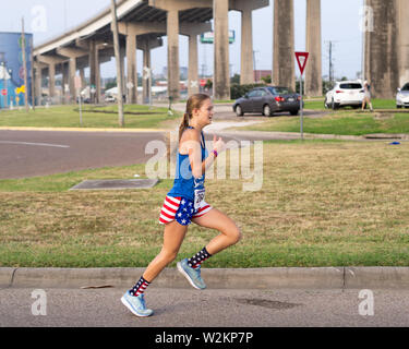 Une jeune femme porter du rouge, blanc et bleu attire l'exécution de la dernière partie des quatre pour la quatrième / 4 Mile Fun Run de Corpus Christi, Texas USA. Banque D'Images