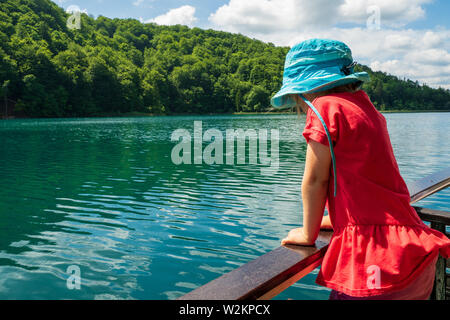 3 ans, à la recherche sur la rambarde d'une croisière ferry sur le lac Kozjak au parc national des Lacs de Plitvice, Plitvice, Croatie Banque D'Images