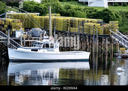 Un homard bateau amarré à un quai haute empilée avec des casiers à homard à New Harbor, Maine. Le petit port pittoresque de pocket est un des derniers ports de travail sur le long de la péninsule Pemaquid midcoast Banque D'Images