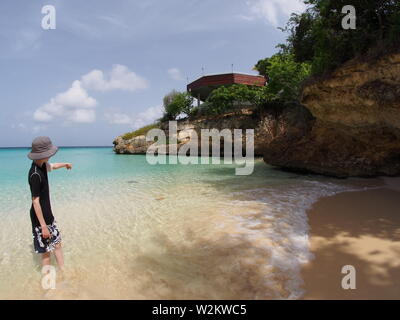 Jeune garçon en montrant une raie nageant dans les eaux peu profondes, Meads Bay, Anguilla, BWI. Banque D'Images