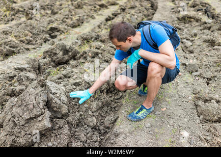 La recherche de l'homme touchant les minéraux du sol brun en Arkansas la saleté paysage pré champ dans Crater de diamants State Park Banque D'Images