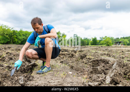 Homme creuser avec une pelle pour toucher les pierres du sol brun en Arkansas la saleté paysage pré champ dans Crater de diamants State Park Banque D'Images