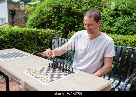 Table d'échecs dans un parc à Hot Springs, Arkansas avec homme jouant au cours de journée d'été assis sur un banc Banque D'Images