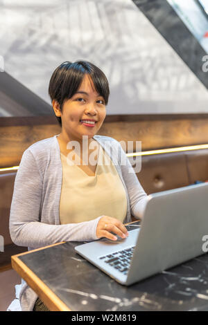 Cheveux courts Smiling Asian woman working with laptop Banque D'Images