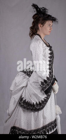 Victorian woman walking in garden dans un noir et blanc robe agitation Banque D'Images