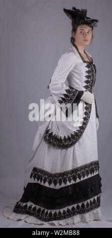 Victorian woman walking in garden dans un noir et blanc robe agitation Banque D'Images