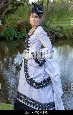 Victorian woman walking in garden dans un noir et blanc robe agitation Banque D'Images