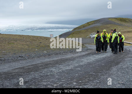 L'Islande, JOKULSARLON - Mai 22, 2019 : les touristes dans l'inflation et des vêtements de sécurité vestes de marcher après un voyage en bateau sur le lagon glaciaire du Jökulsárlón Banque D'Images