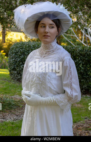 Edwardian femme en blanc ensemble marcher dans un jardin Banque D'Images