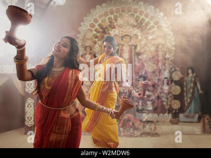 Deux femmes accomplissant un dhunuchi bengali mariés à l'occasion de danse de Durga puja Banque D'Images