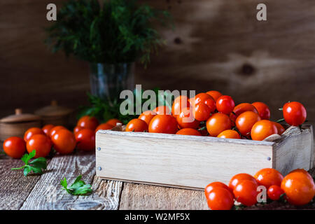 Caisse de produits biologiques fraîchement cueillis tomates cerises rouges sur table en bois rustique, des aliments à base de plantes, Close up, selective focus Banque D'Images
