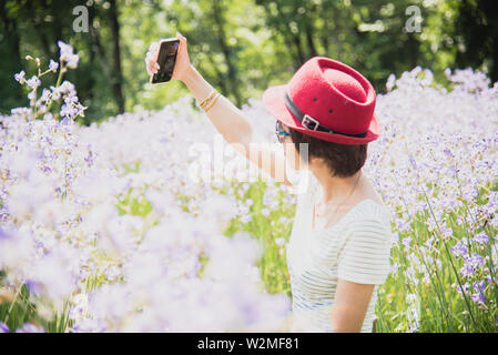 Temps selfies. Des jeunes femmes joyeux par son selfies smart phone dans une prairie violet. Banque D'Images