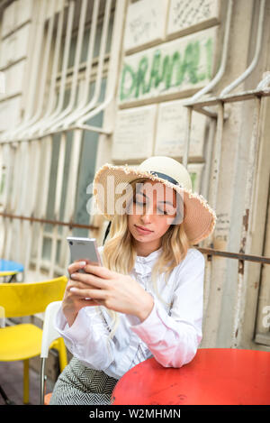 Belle jeune fille belle utilise smart phone alors qu'il était assis à la terrasse d'un café à l'extérieur.concept de vie Banque D'Images