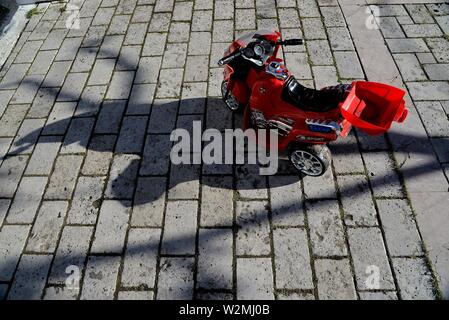 Jouet moto électrique d'ombre sur le sol carrelé. Banque D'Images