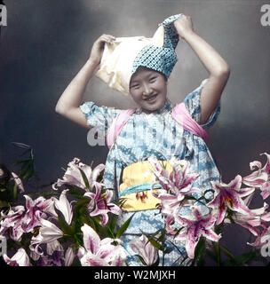 [ 1900 - Japon ] Lys avec Geisha - jolie jeune femme dans des vêtements traditionnels qui posent avec des lis, au début des années 1900. Nobukuni Enami, le photographe, l'a appelée 'l'esprit de lis." du xxe siècle vintage lame de verre. Banque D'Images