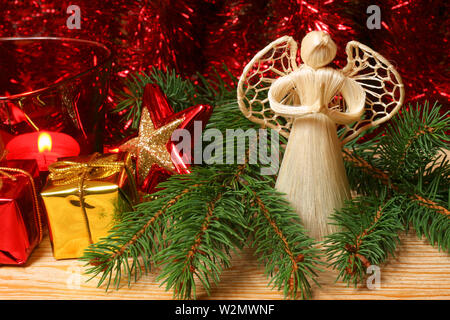 Ange priant dans les branches d'arbre de Noël avec des ornements de Noël rouge Banque D'Images