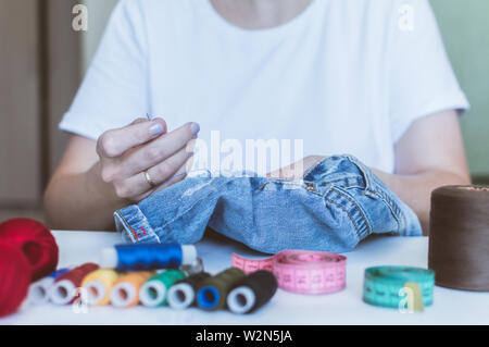 Women's Hands, un tailleur coud des vêtements à une table sur laquelle se trouvent des bobines de fil Banque D'Images