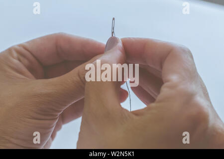 Women's Hands, un tailleur coud des vêtements à une table sur laquelle se trouvent des bobines de fil Banque D'Images