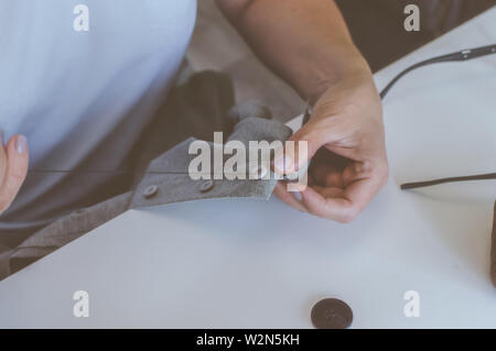 Women's Hands, un tailleur coud des vêtements à une table sur laquelle se trouvent des bobines de fil Banque D'Images