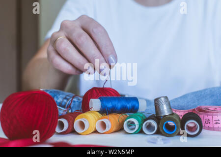 Women's Hands, un tailleur coud des vêtements à une table sur laquelle se trouvent des bobines de fil Banque D'Images