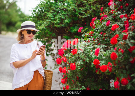 Charmant, joli, élégant et moderne, dame de la rue, faire des achats en ligne via l'internet mobile, en tenant dans les mains. smartphone Banque D'Images