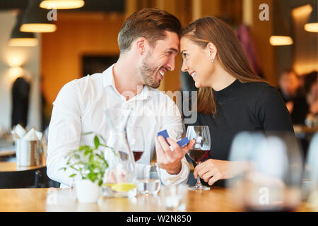 Heureux couple regarde profondément dans l'oeil à la demande en mariage au restaurant Banque D'Images