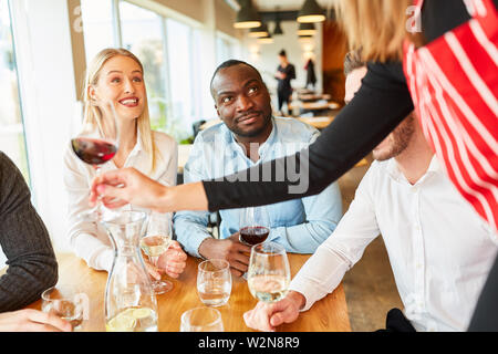 Serveuse ou serveuse en bar ou restaurant sert les clients du vin de table Banque D'Images