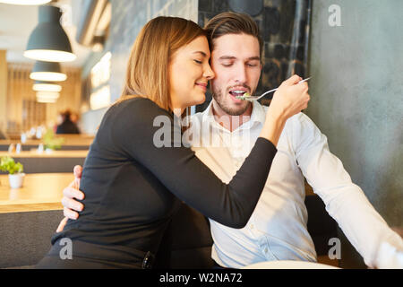 Jeune femme d'amour nourrit son petit ami à dîner au restaurant Banque D'Images