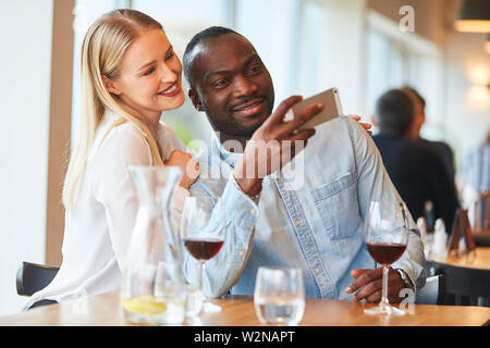Amorous couple multiculturel prend une rendezvousing selfies tandis que dans le restaurant Banque D'Images