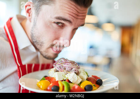 Waiter serving fresh salade grecque comme un savoureux hors-d'œuvre dans le restaurant Banque D'Images