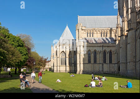 Touristes personnes visiteurs appréciant le soleil de printemps dans Deans Park en dehors de la Minster York North Yorkshire Angleterre Royaume-Uni Grande-Bretagne Banque D'Images