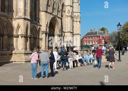 Touristes personnes visiteurs à l'extérieur de l'entrée du transept Minster Sud au printemps York North Yorkshire Angleterre Royaume-Uni Grande-Bretagne Banque D'Images