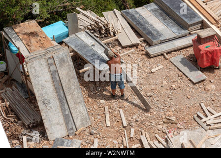 Crète, Grèce. Juin 2019. Un constructeur sur place travaillant avec des planches de bois recyclé Banque D'Images