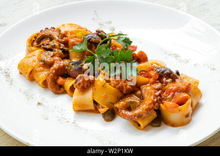 Close up of octopus calamarata pâtes italiennes faites maison sicilienne sauce aux fruits de mer à la tomate basilic,persil,herbes,froid,préparé par profession Banque D'Images