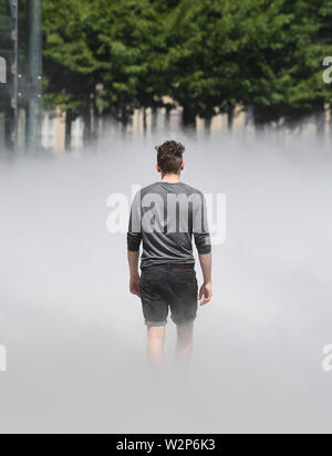 Karlsruhe, Allemagne. 10 juillet, 2019. En face du Centre pour l'art et les médias (ZKM), le brouillard sculpture 'CLOUD À PIED @ZKM. Sculpture de brouillard # 10731" par l'artiste Fujiko Nakaya. Le travail fait partie de l'exposition 'Negativer Raum und Skulptur im Installation 20./21. Jahrhundert" (l'espace négatif la sculpture et l'installation dans le 20e et 21e siècle), qui dure jusqu'à 11.08.2019. Le brouillard s'affiche pendant les heures d'ouverture du mercredi au dimanche dans la période 10h00 à 18h chaque heure complète pendant environ huit minutes. Credit : Uli Deck/dpa/Alamy Live News Banque D'Images