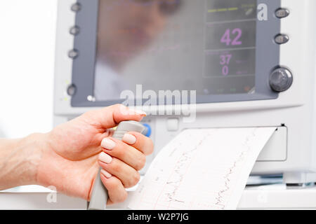 Close-up shot of pregnant woman's hand holding contrôleur de l'Cardiotocograph alias machine de monitorage électronique du foetus (EFM) enregistrement de la fetal heartb Banque D'Images