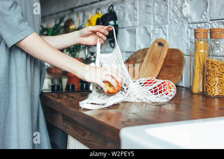 Jeune femme en robe gris pommes tire hors de chiffon tricot chaîne sac shopper Sac dans la cuisine, zéro déchet, slow life Banque D'Images